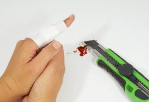 Schnittverletzung. Eine Person hat sich mit einem Cuttermesser in den Finger geschnitten. Dieser wurde mit einem Pflaster verbunden.